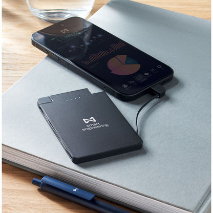 Batería externa negra personalizada conectada a un teléfono móvil sobre una mesa de oficina