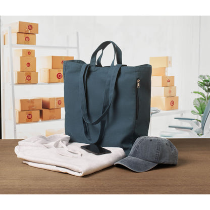 Totebag para playa y compras con asas largas y cortas color marino sobre mesa de madera y junto a un polo blanco, una gorra y un teléfono móvil