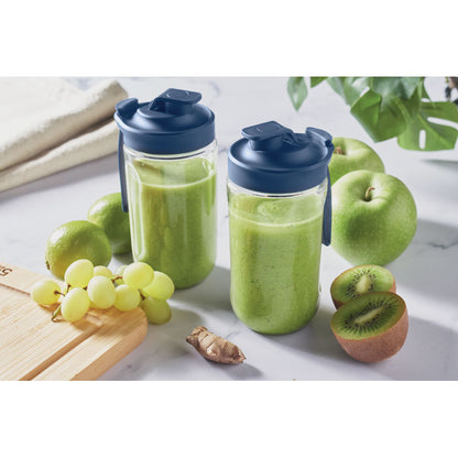 Pareja de vasos llenos de zumo verde sobre una mesa de desayuno con frutas verdes