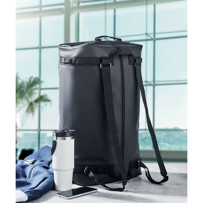 Bolsa mochila grande  de deporte junto a vaso blanco de metal