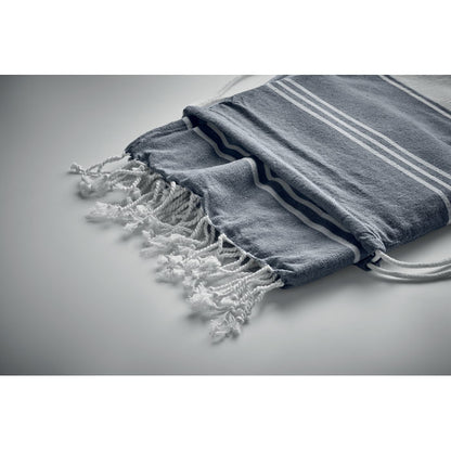 Detalle de toalla con flecos dentro de mochila de algodón azul y blanca