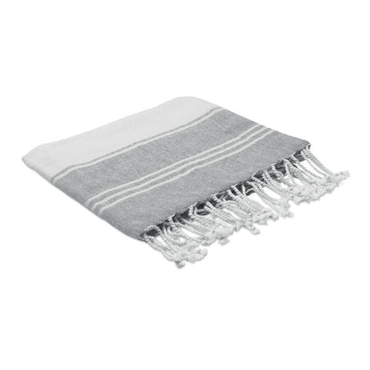 Toalla gris y blanca con flecos doblada