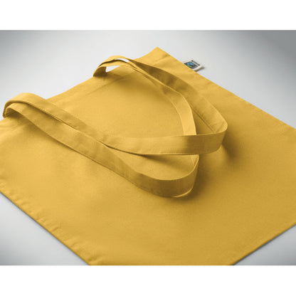 Bolsa amarilla de algodón extendida sobre superficie