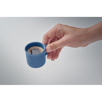 Vista superior de taza de espresso azul con fondo gris