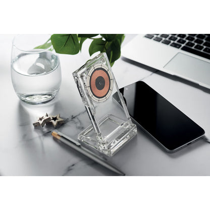 Mesa de mármol con portátil, cargador transparente, boli, móvil y vaso con agua