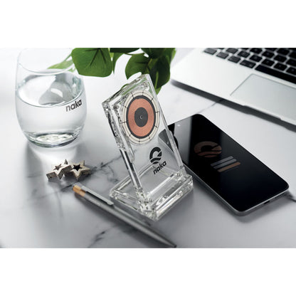 Mesa de mármol con portátil, cargador transparente con logo, boli, móvil y vaso con agua
