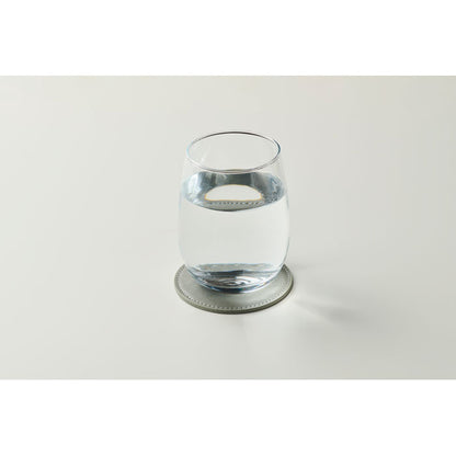 Vaso de agua de cristal sobre posavasos redondo gris