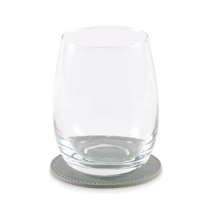 Vaso de agua de cristal sobre posavasos redondo gris
