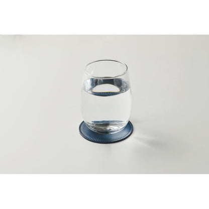 Vaso de agua de cristal sobre posavasos redondo marino