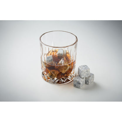 Vaso con bebida y hielos de piedra sobre fondo gris