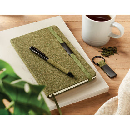 Vista lateral de libreta verde con cierre goma sobre fondo gris