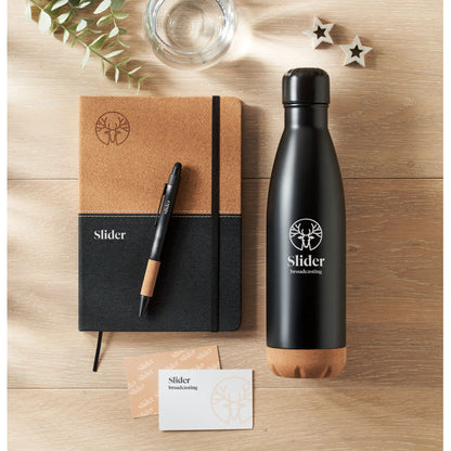 Vista superior de mesa de madera con botella+boli+libreta, negro con detalles de corcho y logo impreso