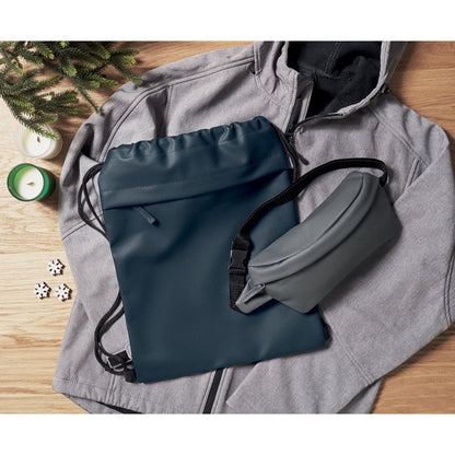 Mochila de cuerdas marino y riñonera sobre chaqueta gris con capucha en mesa de madera