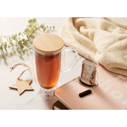 Taza con infusión con tapa de bambú sobre mesa con detalles decorativos 