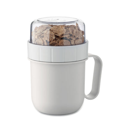 Taza blanca con contenerdor con cereales en parte superior