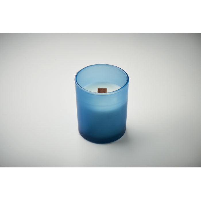 Diseño elegante de vela en vidrio azul con mecha de madera, ideal para crear ambiente acogedor.