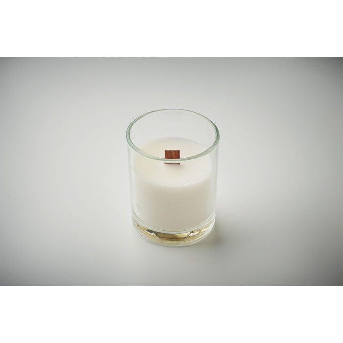 Vista lateral de vela de cera vegetal en recipiente de vidrio, con mecha de madera y fragancia a vainilla.