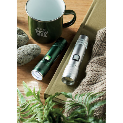 Taza de metal ,linterna verde y linterna gris personalizadas con logotipo sobre una mesa de madera
