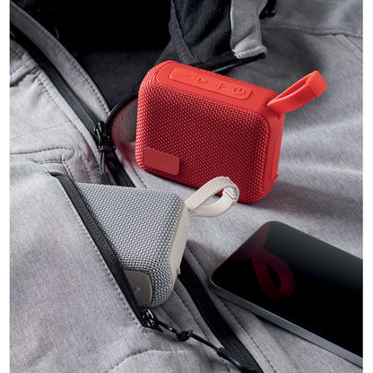 Chaqueta gris con altavoz blanco en bolsillo y azltavoz rojo con asa