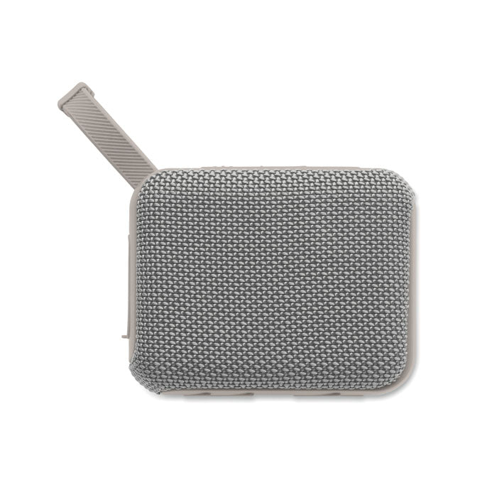 Vista superior de un altavoz inalámbrico de 5 W en color gris, con acabado de tejido RPET y diseño compacto.