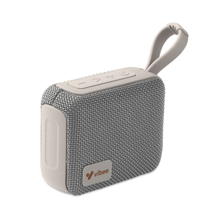 Vista lateral de un altavoz inalámbrico de 5 W en color gris con textura de tejido y botón de control en la parte superior.