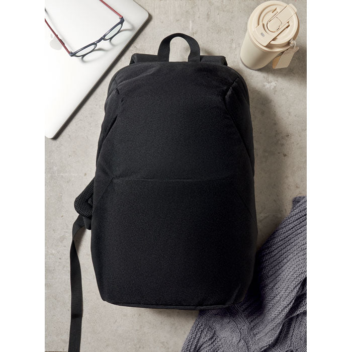 Diseño minimalista de mochila negra, fabricada en poliéster, ideal para transportar un portátil de 15". Incluye detalles de compartimentos.