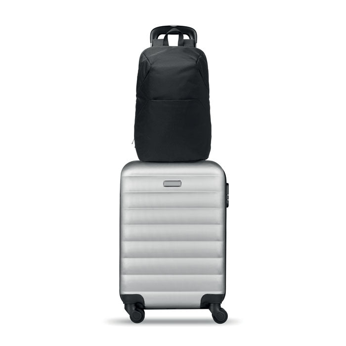 Vista frontal de una mochila negra sobre una maleta plateada, ideal para viajes y transporte de dispositivos. ARLON - Mochila para portátil de 15".