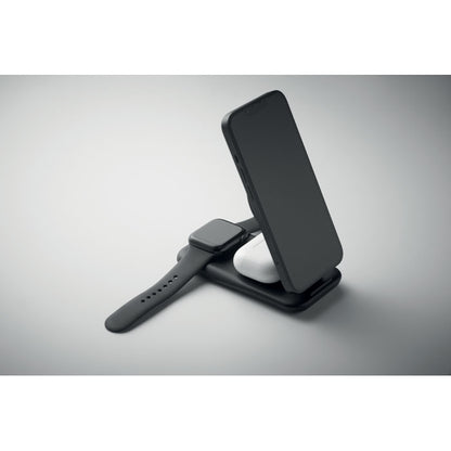 Móvil, auriculares y reloj cargando sobre base de carga negra