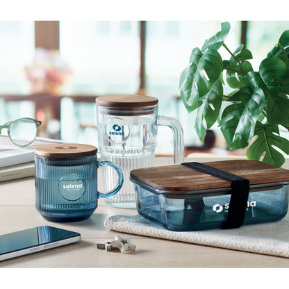 mesa con fiambrera de vidrio azul, taza acanalada de vidrio azul y jarra de cristal