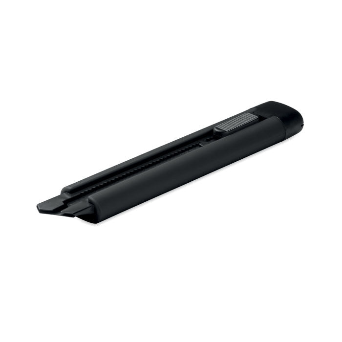 Cúter retráctil grande negro con carcasa de ABS y hoja de acero al carbono, dimensiones compactas.