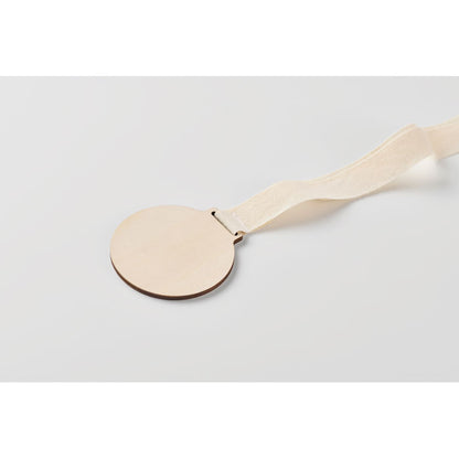 Detalle de la medalla de madera sobre superficie clara
