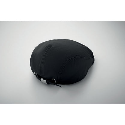Gorra Newsboy negra apoyada sobre superficie