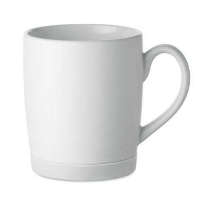 Taza blanca mate con base negra vista en ángulo sobre fondo gris