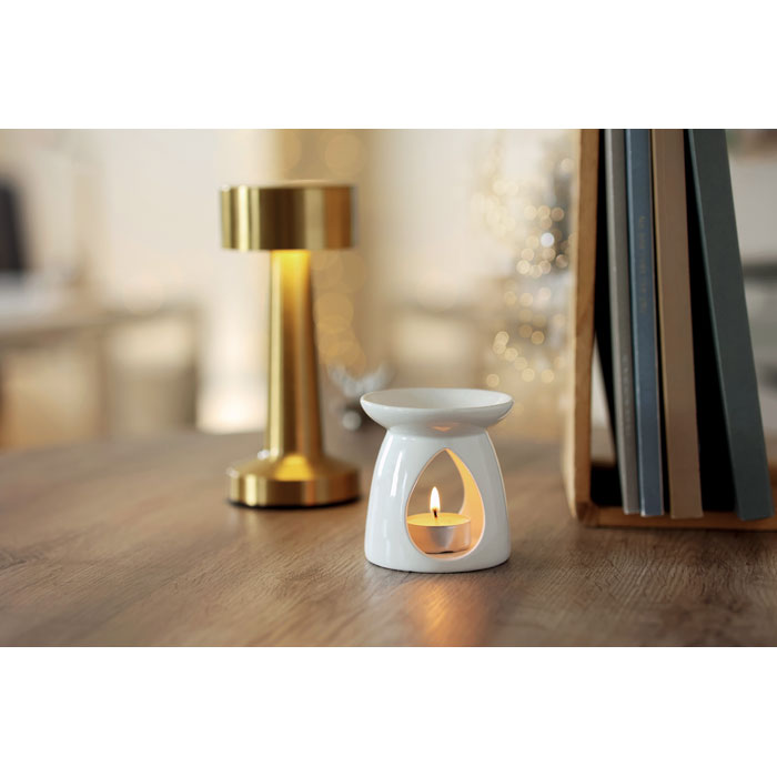 SAGRADA - Quemador de vainilla con vela en un ambiente acogedor, con vela encendida y detalles decorativos.