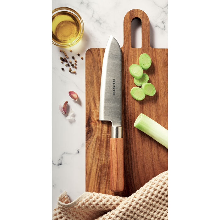 SLICE - Cuchillo chef madera de haya sobre tabla de madera con vegetales y aceite de oliva.