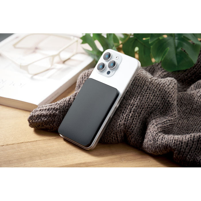 SLIMVOLT - Powerbank ultrafino de 20 W colocado sobre un smartphone blanco en una mesa de madera.