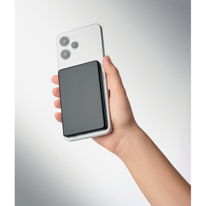 CORE - Powerbank magnético de 5000 mAh en mano junto a un smartphone.