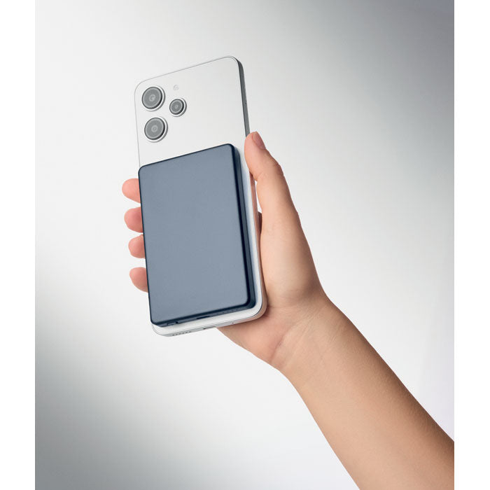 CORE - Powerbank magnético de 5000 mAh siendo sostenido detrás de un smartphone, ideal para cargas inalámbricas y cableadas.