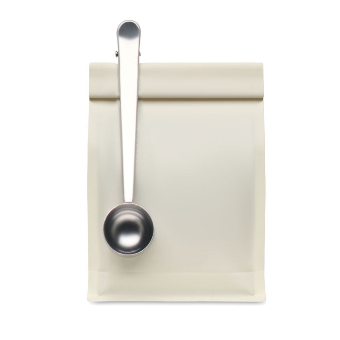 SPOONCOOP - Cuchara con clip para bolsa sobre una bolsa beige, ideal para medir café y proteínas.