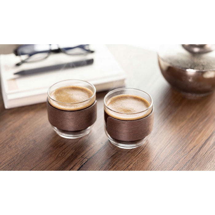 BOGOTA SET - Set vasos café banda de nogal, dos tazas de café de vidrio con banda de madera de nogal sobre una mesa.