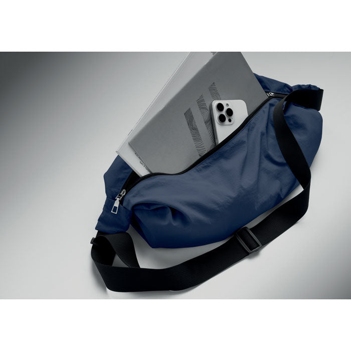 SLING - Bolsa urbana cruzada de nailon en color azul con tablet y teléfono móvil dentro.