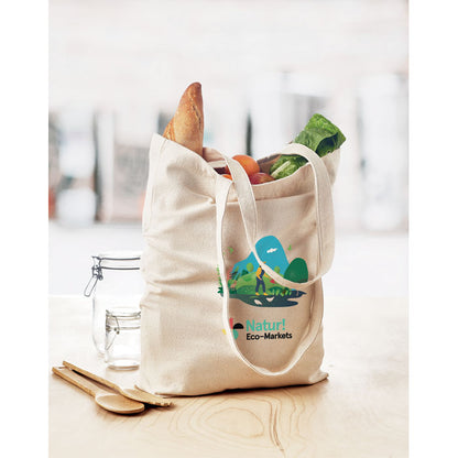 Bolsa de la compra personalizada con logotipo a varios colores sobre mesa de cocina con alimentos en su interior