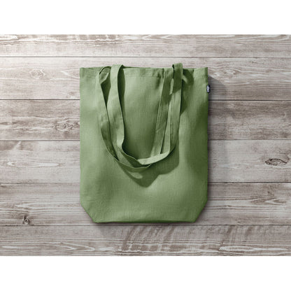 Totebag verde con asas largas sobre mesa de madera