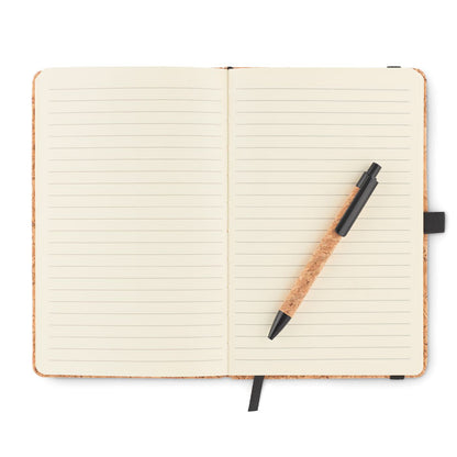 Libreta A5 abierta con hojas rayadas y bolígrafo de corcho con detalles en negro