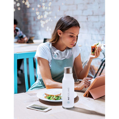 Mujer comiendo frente a una tablet con una botella personalizada con un logotipo
