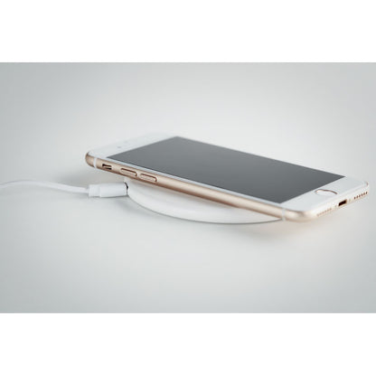 Teléfono móvil cargando sobre cargador inalámbrico sobre fondo gris