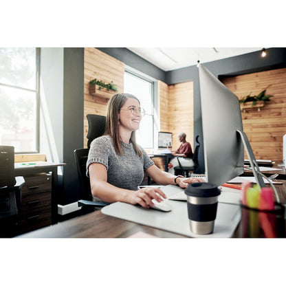 Mujer en una mesa de oficina con un vaso de acero inox. con tapa y faja de silicona negra al lado