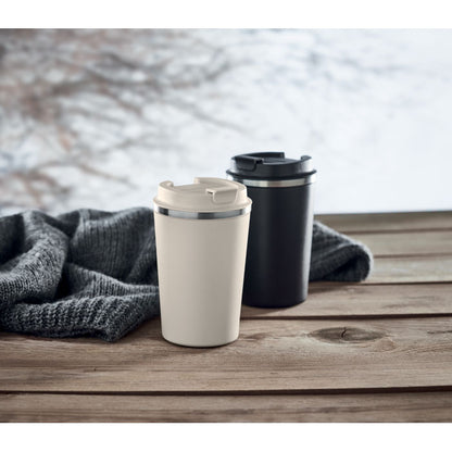 Vaso de acero inoxidable blanco y otro negro sobre superficie de madera en un paisaje invernal