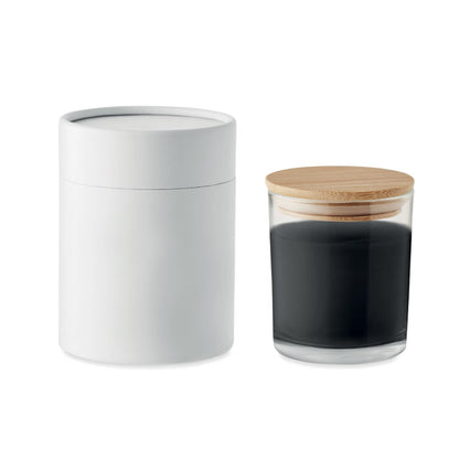 Vela negra de vidrio con tapa de madera y caja cilíndrica al lado