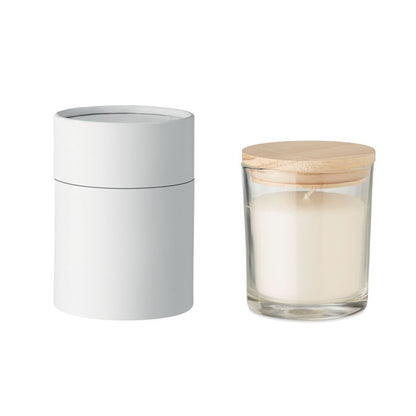 Vela con envase de cristal y tapa de bambú. Caja blanca cilíndrica al lado